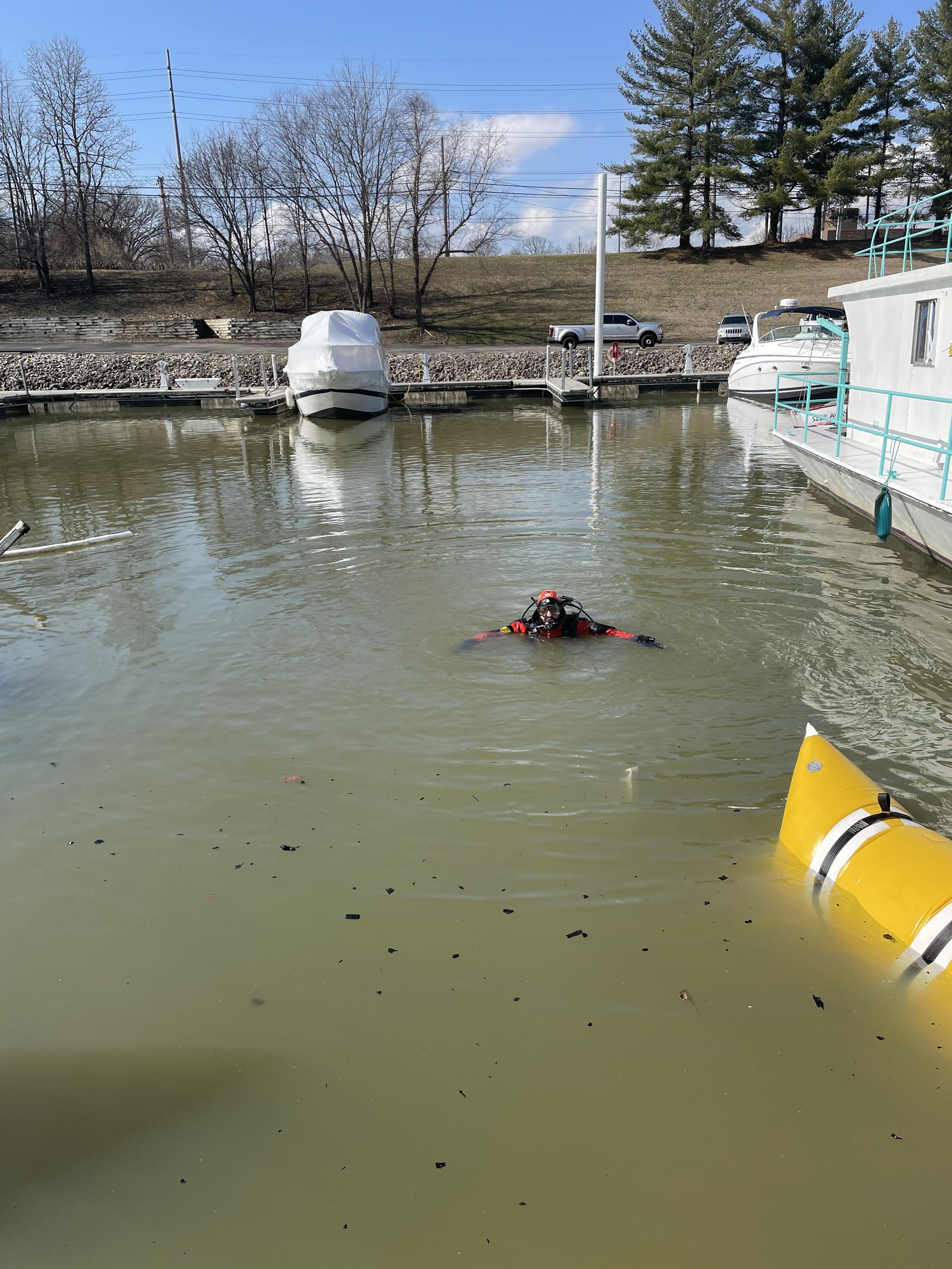 Diver is setting lift bags to recover what is left of sunken houseboat from a fire.