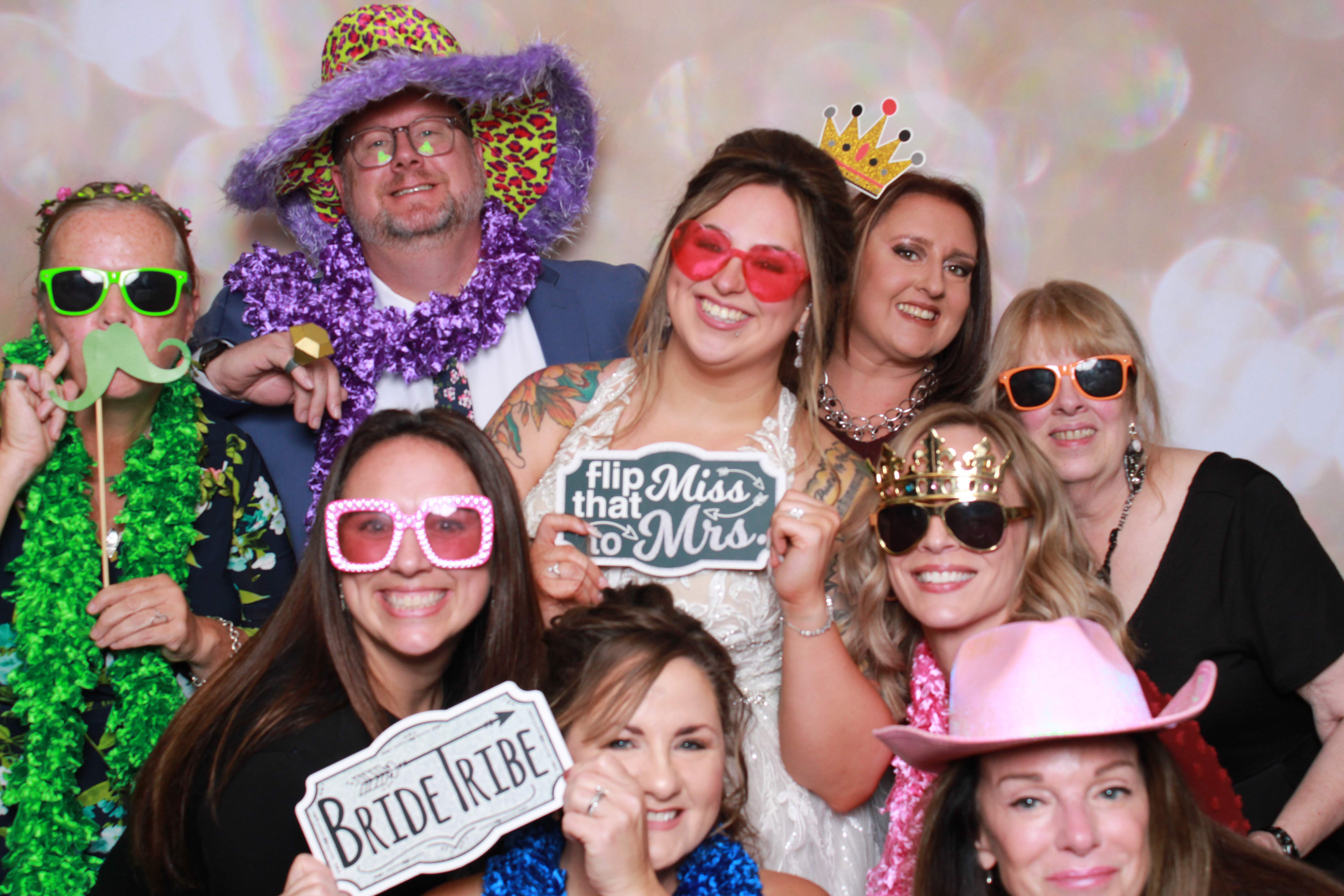 Bride and friends in fun costumes, enjoying a wedding photo booth with props and smiles