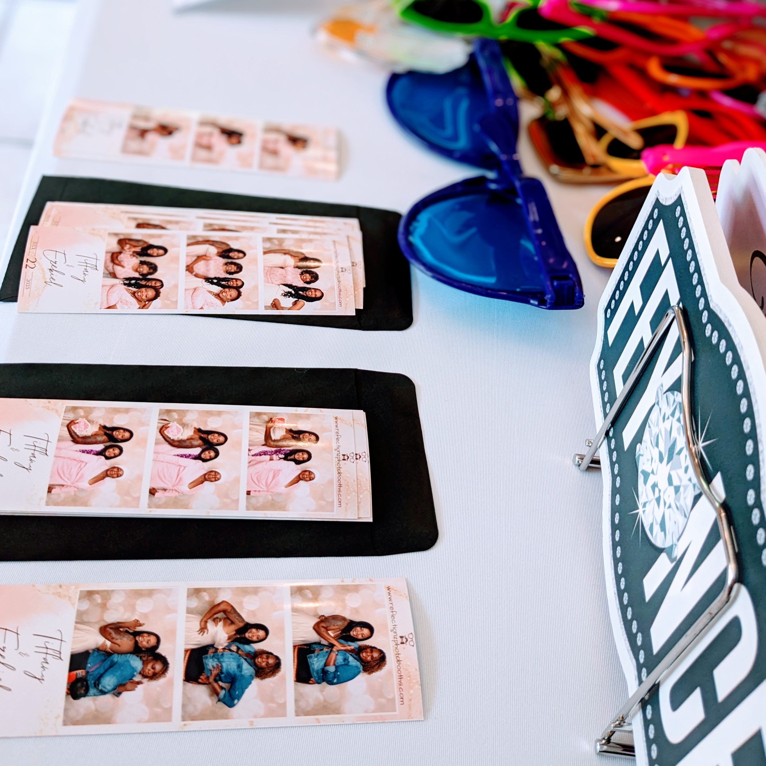 Photo booth prints and colorful props displayed on a table at an event.
