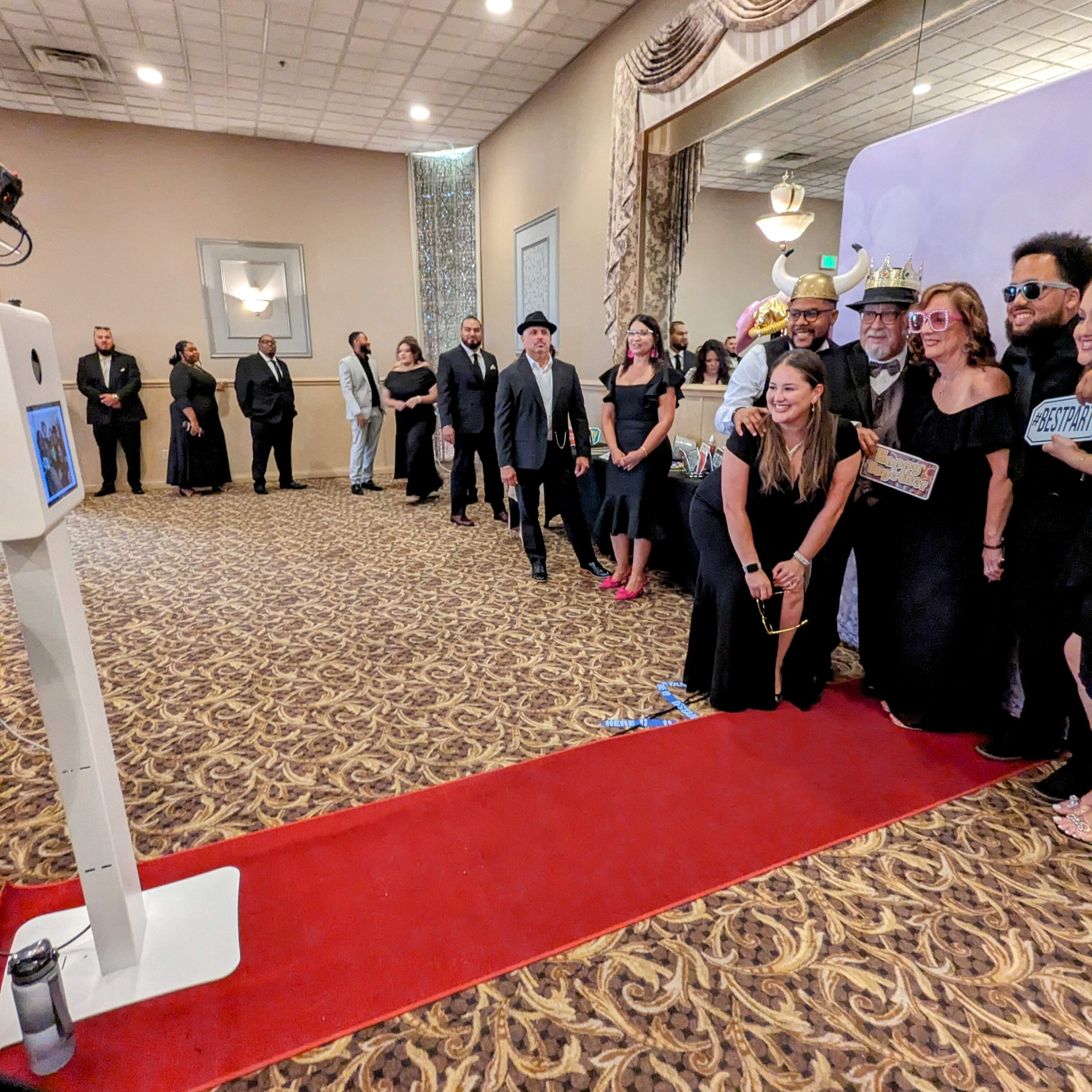 Guests posing at a photo booth during an elegant gala event, enjoying a fun red carpet experience.