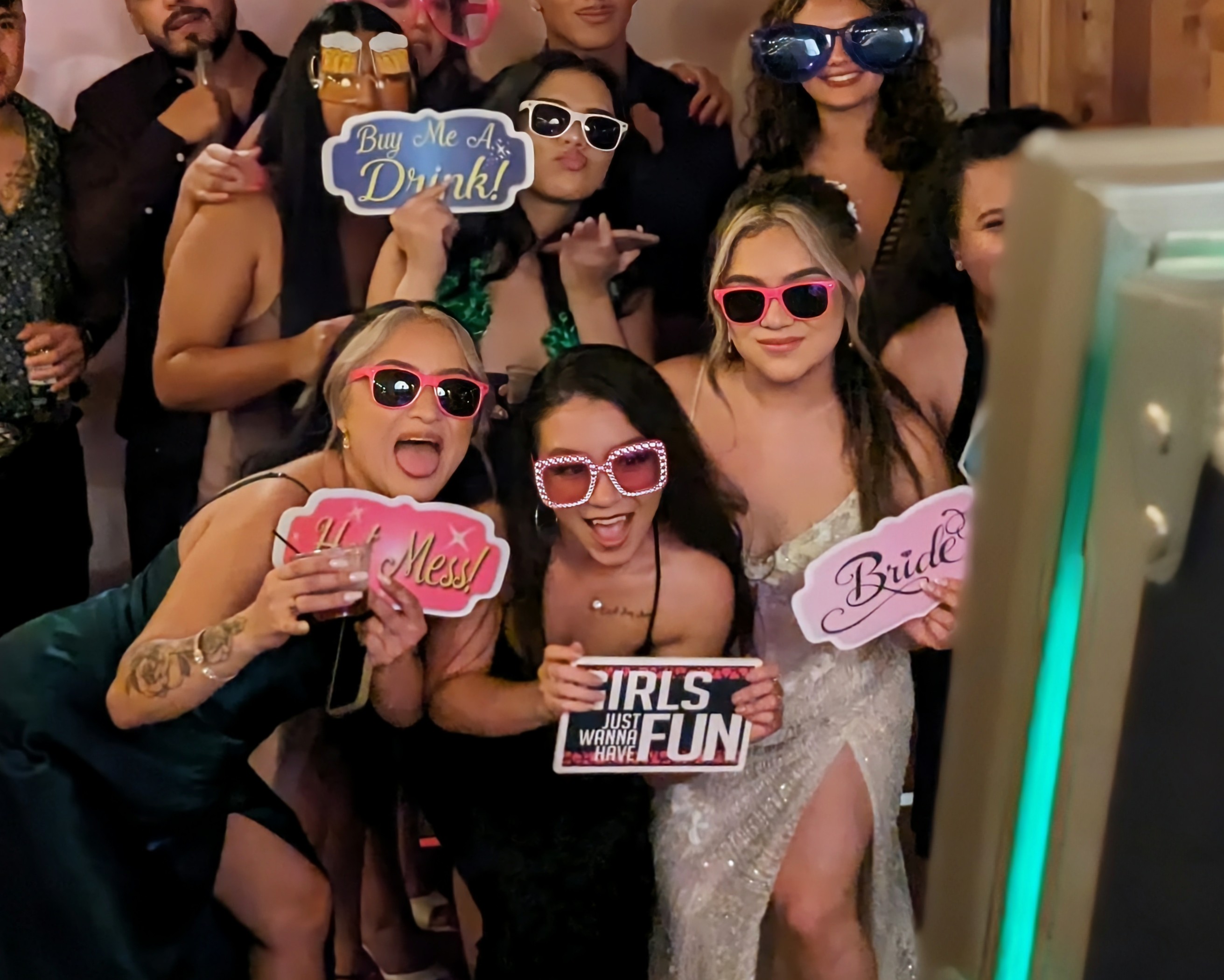 Group of friends celebrating with fun props at a wedding photo booth.